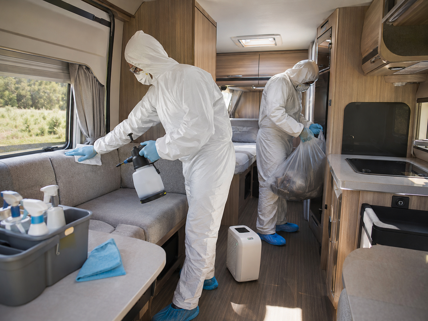 Techniciens en combinaison de protection réalisant un nettoyage spécialisé après un décès dans un camping-car